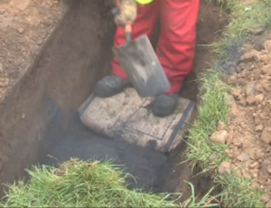 The roadside excavation for a broadband cabinet with a bag of Conducrete emptied in to the base, and another bag about to be opened