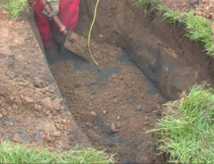 The roadside excavation for a broadband cabinet with earthing installed and native soil being backfilled