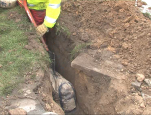 The roadside excavation for a broadband cabinet with bag of Conducrete in the duct trench